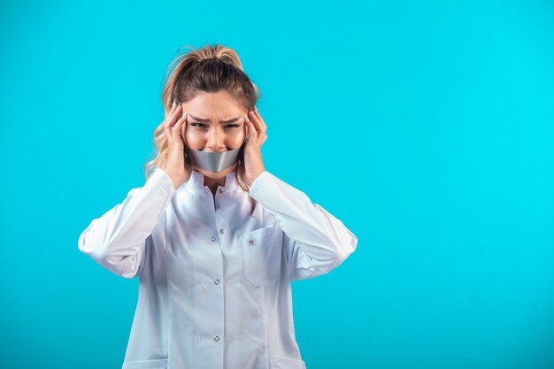 Female doctor in white uniform covering her mouth and ears.