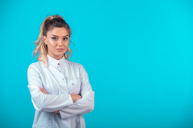 Female doctor in white uniform looks serious. 