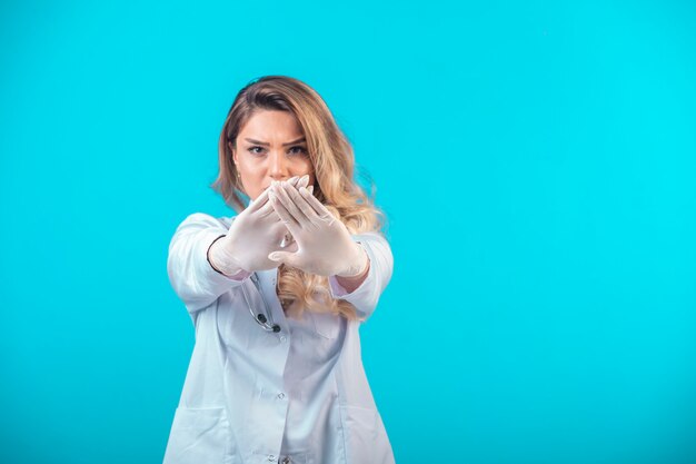 Female doctor in white uniform preventing and stopping something.