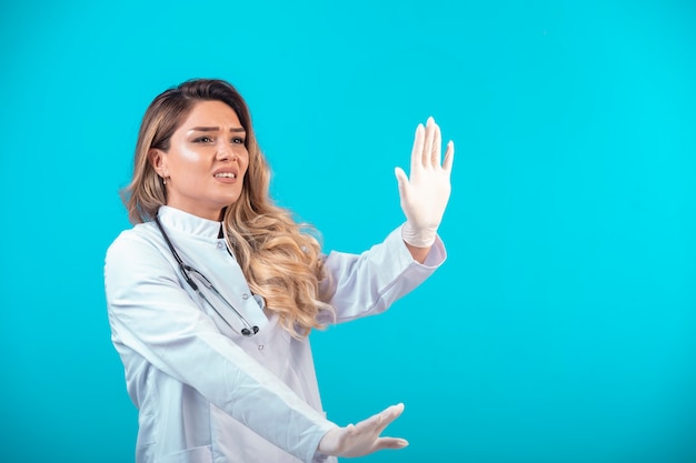 Female doctor in white uniform stopping something.