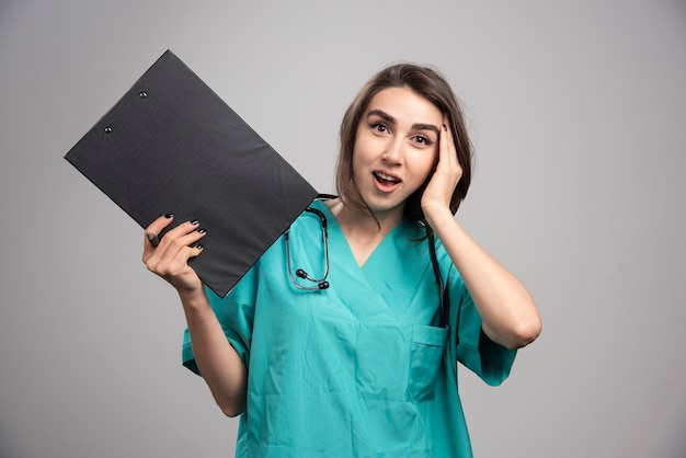 Female doctor with clipboard shocked about news. High quality photo