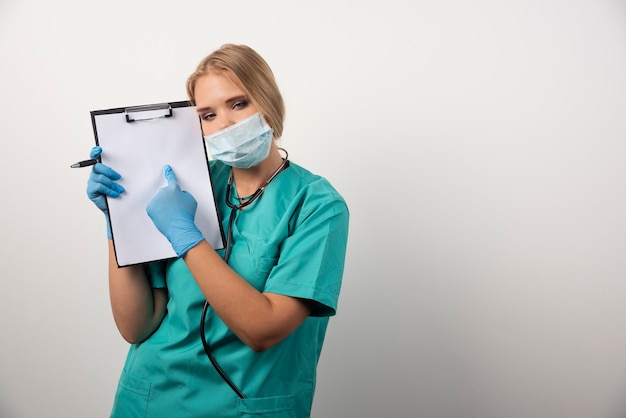 Female doctor with clipboard and wearing protective mask.