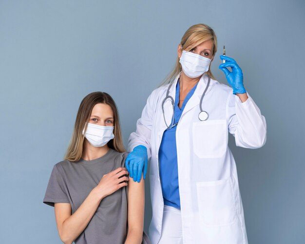 Female doctor with medical mask giving vaccine to woman