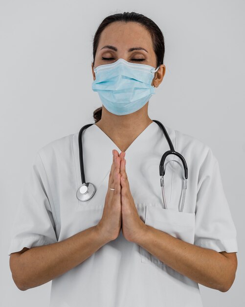 Female doctor with medical mask praying