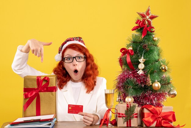 female doctor with present and bank card on light yellow