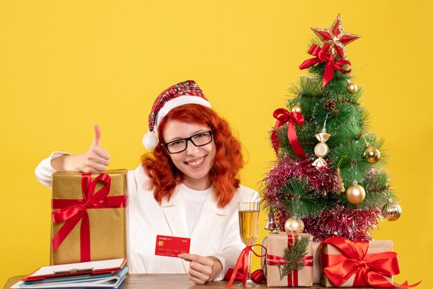 female doctor with present and bank card on yellow