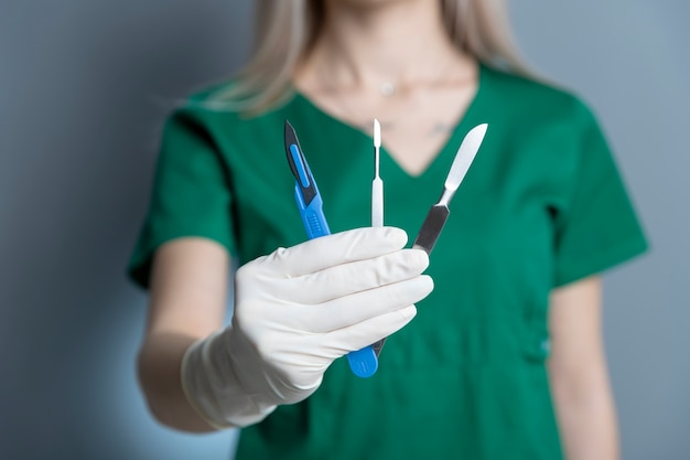 Female doctor with rubber glove holding scalpel  and other instruments