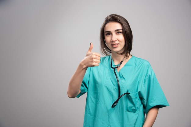 Female doctor with stethoscope giving thumbs up. High quality photo