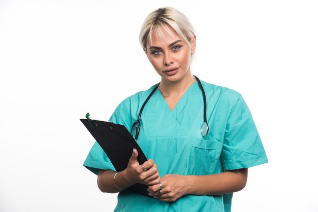 Female doctor with stethoscope holding clipboard on white surface