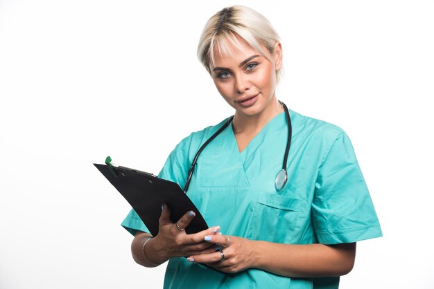 Female doctor with stethoscope holding clipboard on white surface