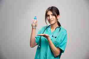 Бесплатное фото Женщина-врач со стетоскопом держит бутылку с распылителем
