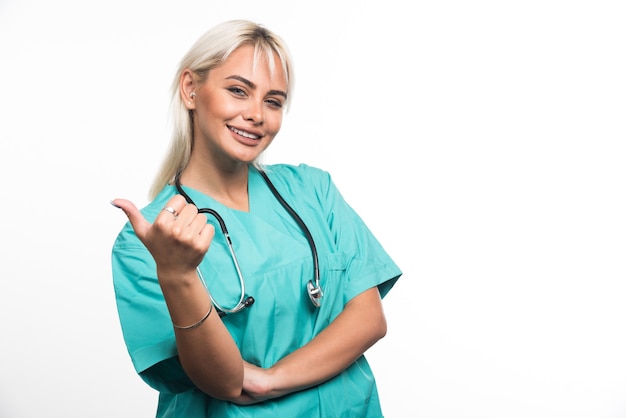 Female doctor with stethoscope pointing finger on white surface