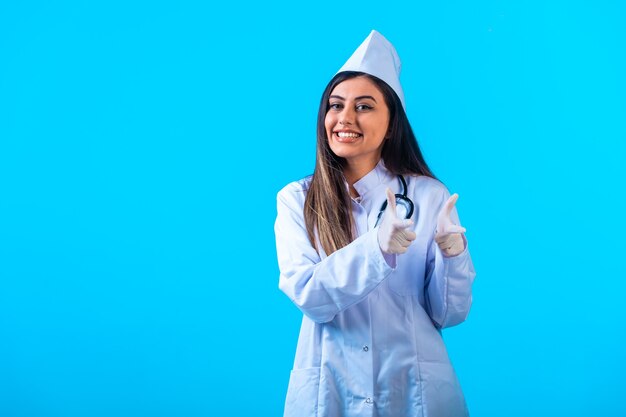 Female doctor with stethoscope pointing at something ahead. 