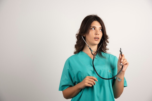 Female doctor with stethoscope posing on white.