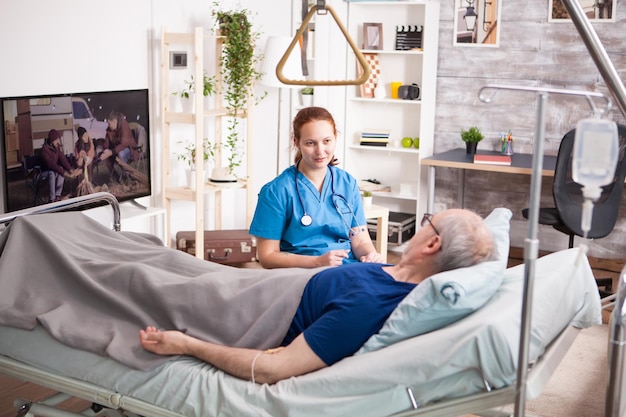 Foto gratuita medico femminile con lo stetoscopio che condivide il comfort con il vecchio in casa di cura.