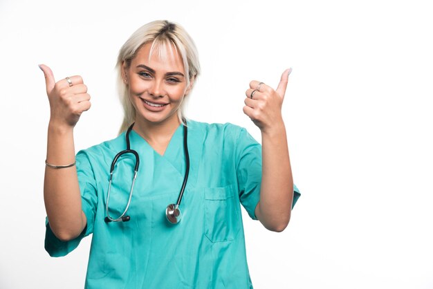 Female doctor with stethoscope showing thumbs up on white surface