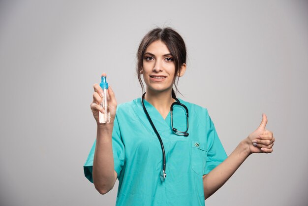 Female doctor with stethoscope spraying bottle