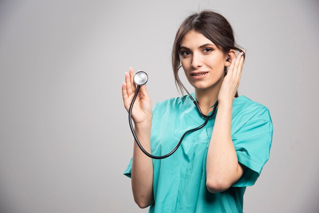 灰色の上に立っている聴診器を持つ女性医師