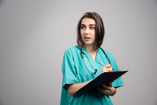 Female doctor with stethoscope writing on clipboard. High quality photo