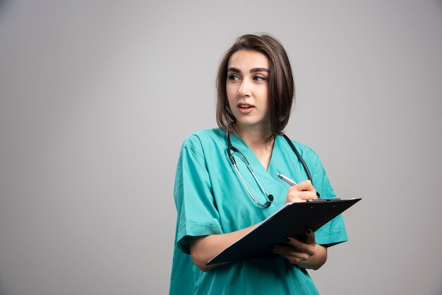 クリップボードに聴診器を書いている女性医師。