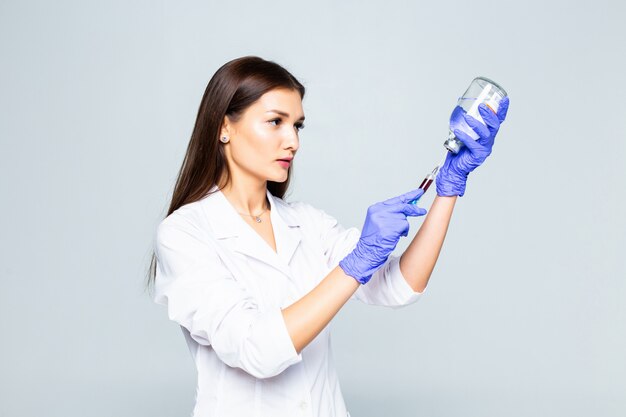 Female doctor with syringe preparation to do a inoculation isolated on white wall