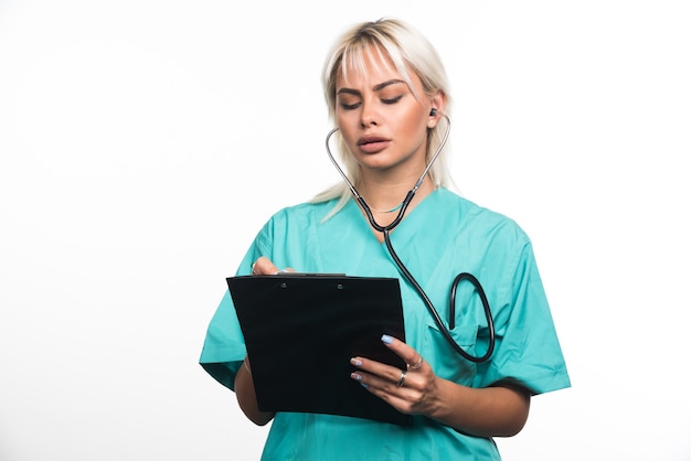 Female doctor writing something on clipboard on white surface