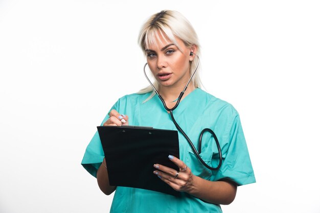 Female doctor writing something on clipboard on white surface