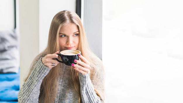 Female drinking coffee sitting at window