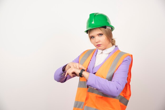 Female employee pointing time on white wall. 