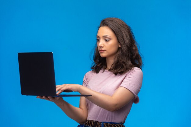 Female employee with a black laptop having video call and looks serious.