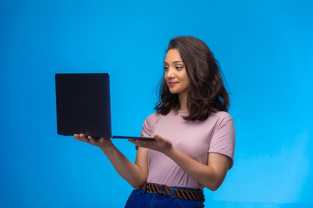 Female employee with a black laptop having video call and smiling.