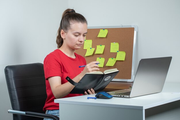 Female employee working at the laptop and taking notes