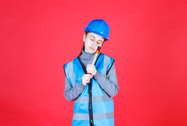 Female engineer in blue helmet holding a wooden ax and sleeping