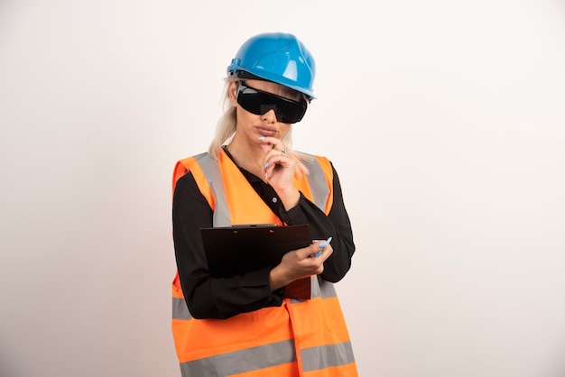 Female engineer in glasses looking at clipboard on white background. High quality photo