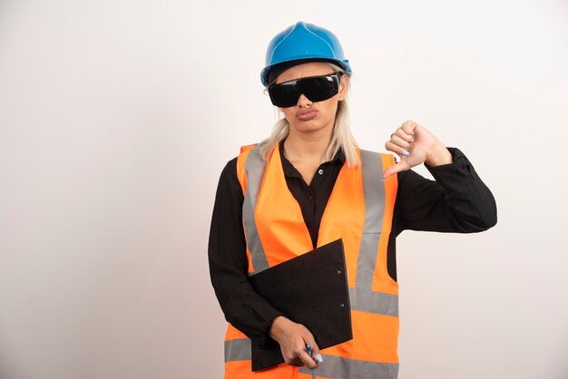 Female engineer in glasses making thumbs down on white background. High quality photo