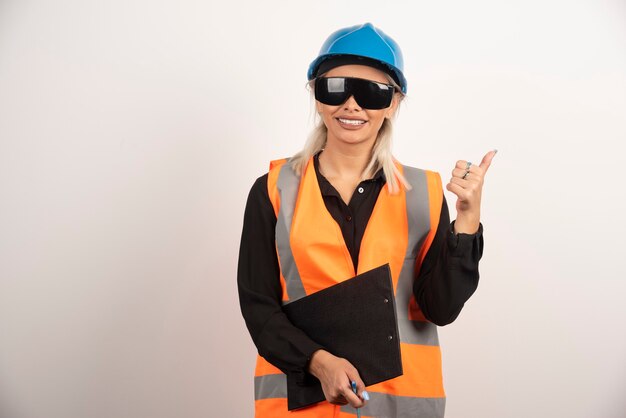 白い背景に親指を立てる眼鏡の女性エンジニア。高品質の写真