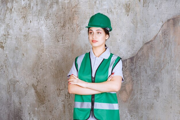 緑の制服とヘルメットの交差する腕の女性エンジニアとプロに見えます。