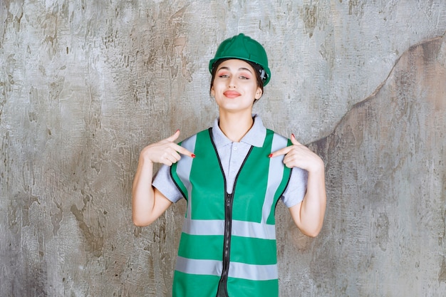 緑の制服とヘルメットの女性エンジニアが自己紹介します。