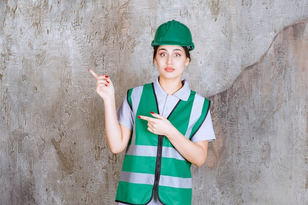 Female engineer in green uniform and helmet showing left side with emotions. 