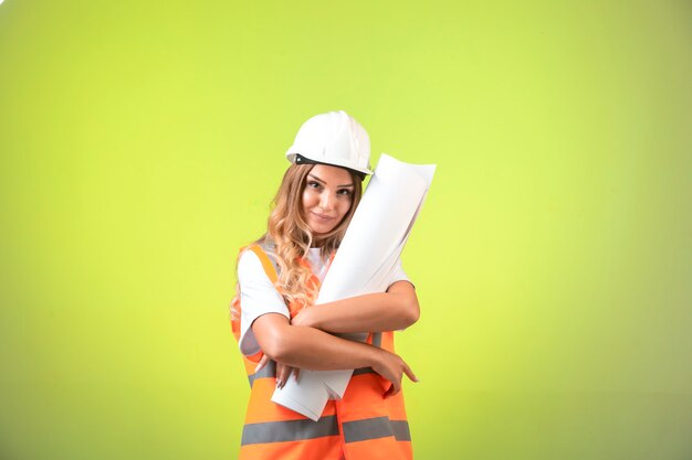 Female engineer in helmet and gear holding the construction plan