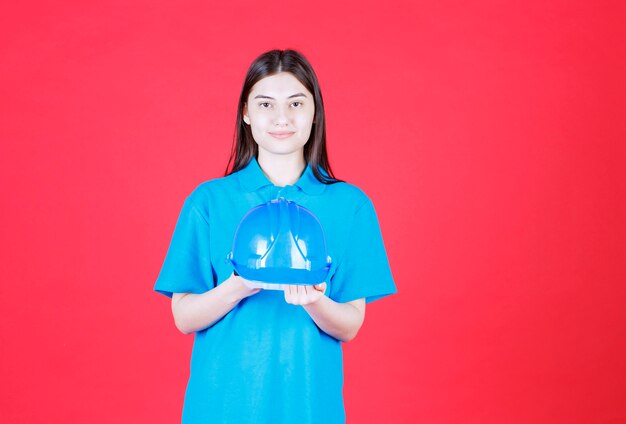 Female engineer holding blue helmet