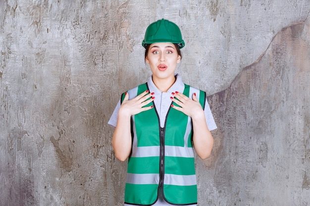 무료 사진 고마움을 느끼는 녹색 유니폼과 헬멧을 쓴 여성 엔지니어