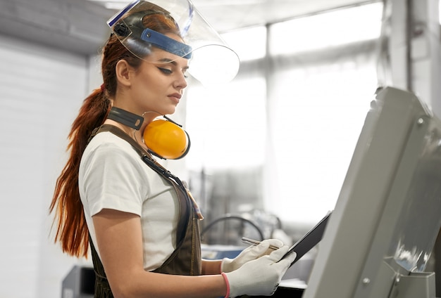 Free photo female engineer in protective clothes working on factory.