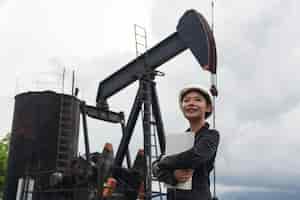 無料写真 空の作業油ポンプの横に立っている女性エンジニア。