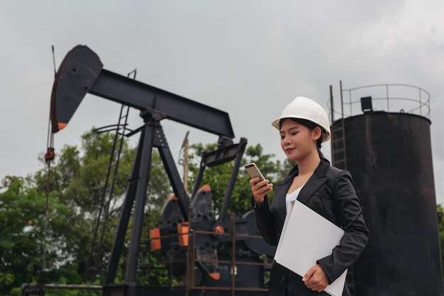 Free photo female engineer standing beside working oil pumps with a sky .