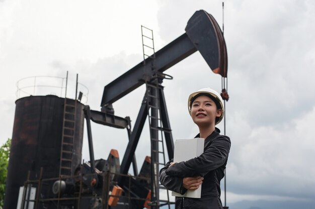 Female engineer standing beside working oil pumps with a sky .