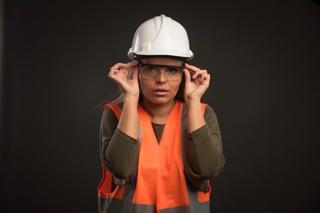 흰색 헬멧, 안경 및 장비를 착용하는 여성 엔지니어.
