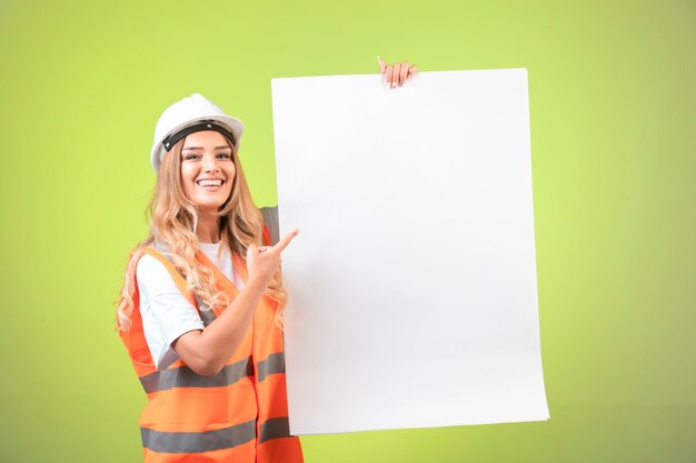 Female engineer in white helmet and gear introducing the construction plan 