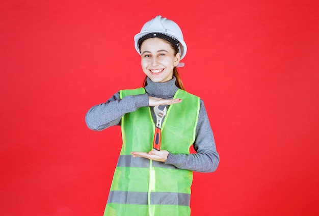 無料写真 金属製のレンチを保持している白いヘルメットを持つ女性エンジニア。