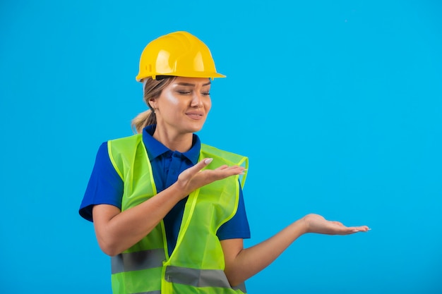 Female engineer in yellow helmet and gear pointing something.